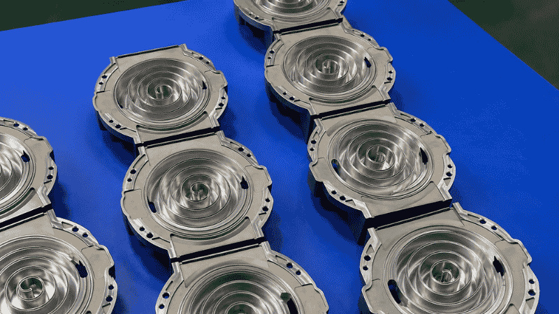 Vacuum die cast aluminum parts arranged on a blue worktable after machining